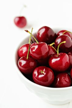 some cherries are sitting on a wooden table with water droplets all over them,