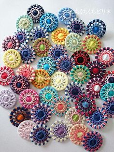 a bunch of colorful buttons sitting on top of a white table next to each other