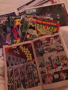 a bunch of comic books laying on top of a bed next to eachother