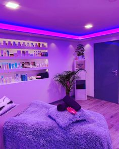 a spa room with purple lighting and towels on the bed