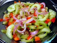 a salad with onions, carrots and celery in a glass bowl on a table