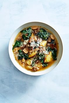 a white bowl filled with pasta and spinach covered in parmesan cheese on top