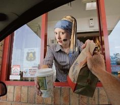 a woman with a bandana is handing something out of a window to someone else