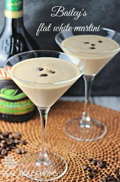 two glasses filled with white martinis sitting on top of a table