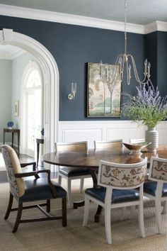 an elegant dining room with blue walls and white trimmings, is pictured in this image