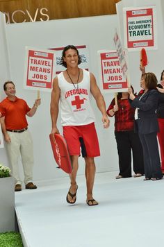 a man is walking down the runway with signs in his hand and holding a tennis racquet