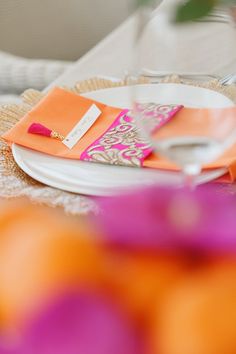 an orange and pink place setting on a table