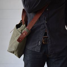 a man wearing a black shirt is holding a green bag and his cell phone in his hand