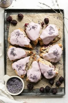 lavender scones with icing and blackberries on a tray