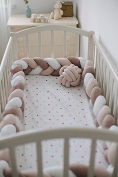 a baby crib with a stuffed animal in it's center and pillows on the bed