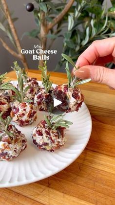 someone is holding up some appetizers on a plate with rosemary sprigs