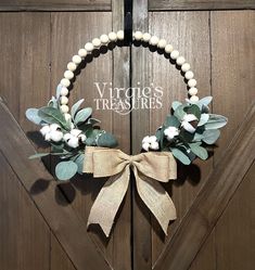 a wreath with cotton and greenery is hanging on the front door