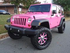 a pink jeep is parked on the street