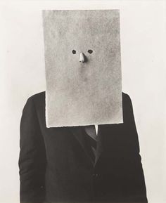 a man in a suit and tie holding up a paper with a face on it