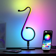 a lamp that is on top of a desk next to a cell phone and remote control