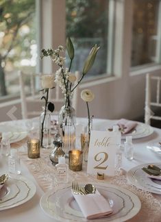 the table is set with plates, silverware and flowers in vases on it