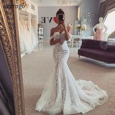 a woman taking a selfie in front of a mirror wearing a white wedding dress