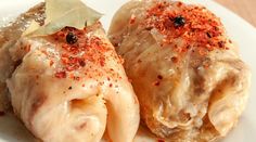 two ravioli stuffed with cheese and spices on a white plate next to a leaf