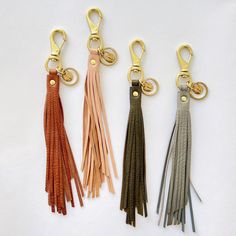 three different colored leather tassels with gold metal hooks on each side and a key chain attached to them