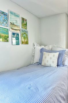 a bedroom with blue and white bedding and pictures hanging on the wall above it