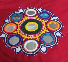 a colorful design on a red cloth with circles and dots in the center, surrounded by smaller circles