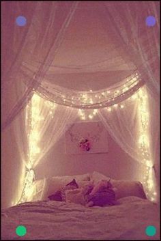 a bed with lights on the headboard and canopy over it in a room that is lit up