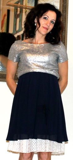 a woman standing in front of a mirror wearing a dress with sequins on it