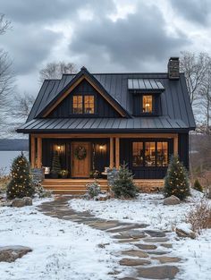 a black and white house with christmas trees on the front porch