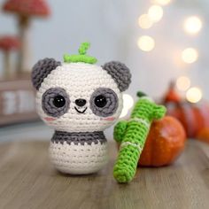 a crocheted panda bear next to carrots on a wooden table with lights in the background