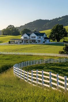 a large white house sitting on top of a lush green field next to a fence