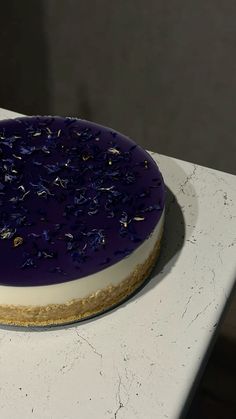 a cake with purple frosting and sprinkles sitting on top of a counter