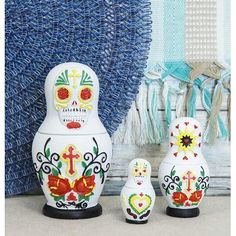 three white and red day of the dead dolls next to a blue wall with tassels