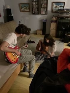 two people are playing guitars in the living room