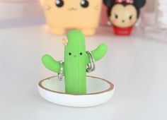 a green cactus keychain sitting on top of a white counter next to other small toys