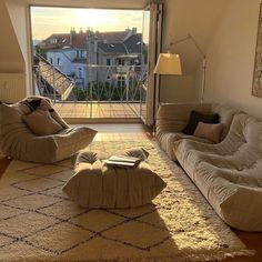 a living room with two couches and a book on the floor in front of an open window