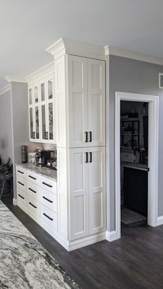 a kitchen with white cabinets and gray walls