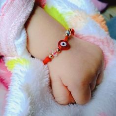 a close up of a baby's hand wearing a bracelet with an evil eye