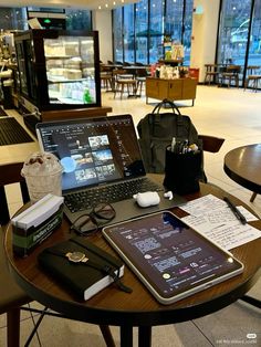 an open laptop computer sitting on top of a wooden table next to a bag and other items