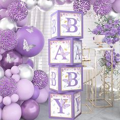 purple and silver baby shower decorations with balloons in the shape of cubes, flowers and butterflies