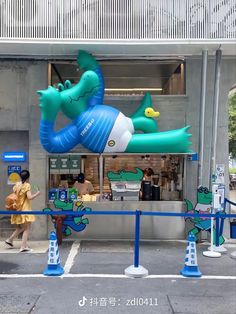 an inflatable dragon is on display at the entrance to a restaurant with people walking by