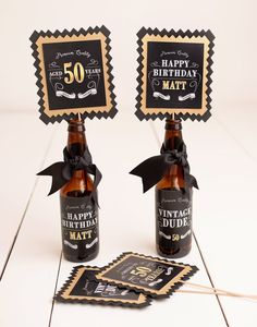 two beer bottles with black and gold labels on them