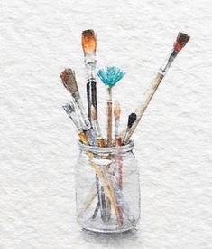 a glass jar filled with lots of paint brushes