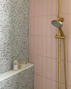 the shower head is gold and pink in this bathroom with black speckles on the walls