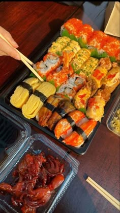 there are many different types of sushi on the trays with chopsticks