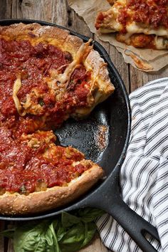 a deep dish pizza in a cast iron skillet with one slice missing from it