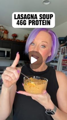 a woman with purple hair is holding a bowl of food and pointing to the camera