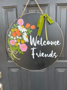 a welcome sign hanging on the front door to someone's house with flowers painted on it