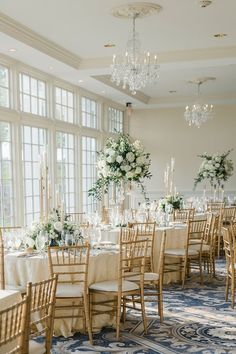 the tables are set up with white flowers and centerpieces for an elegant wedding reception