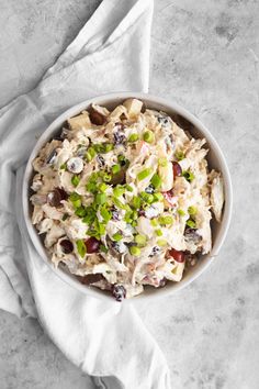 a white bowl filled with chicken salad on top of a table next to a napkin