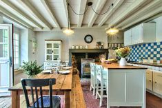 an open kitchen and dining area with wood flooring, white cabinets and blue checkered backsplash